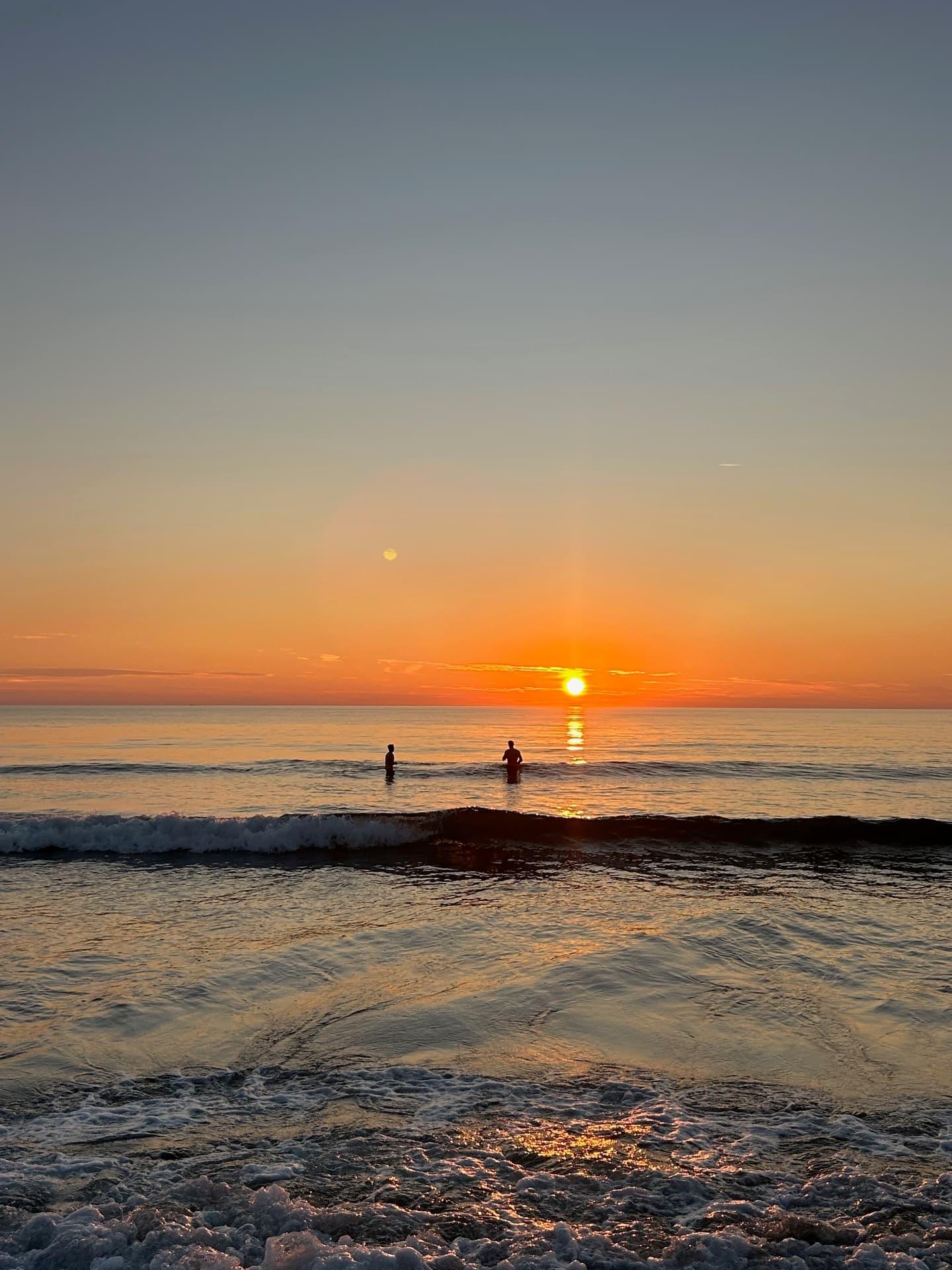 Crew swimming in the ocean at sunset