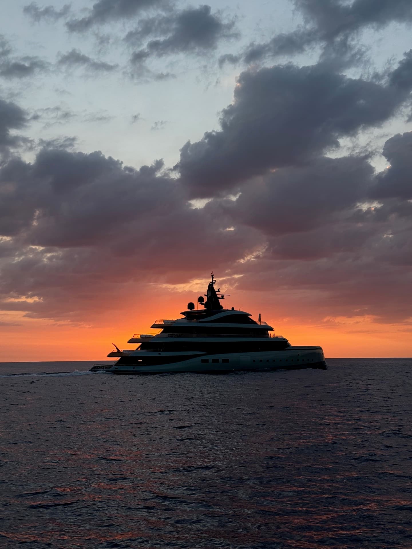 Superyacht silhouette against a dramatic sunset at sea